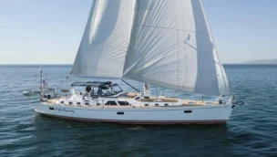 Profile view of a Hylas 70 cruising sailboat underway, highlighting its sleek Germán Frers hull design, white deckhouse, and classic cutter rig.