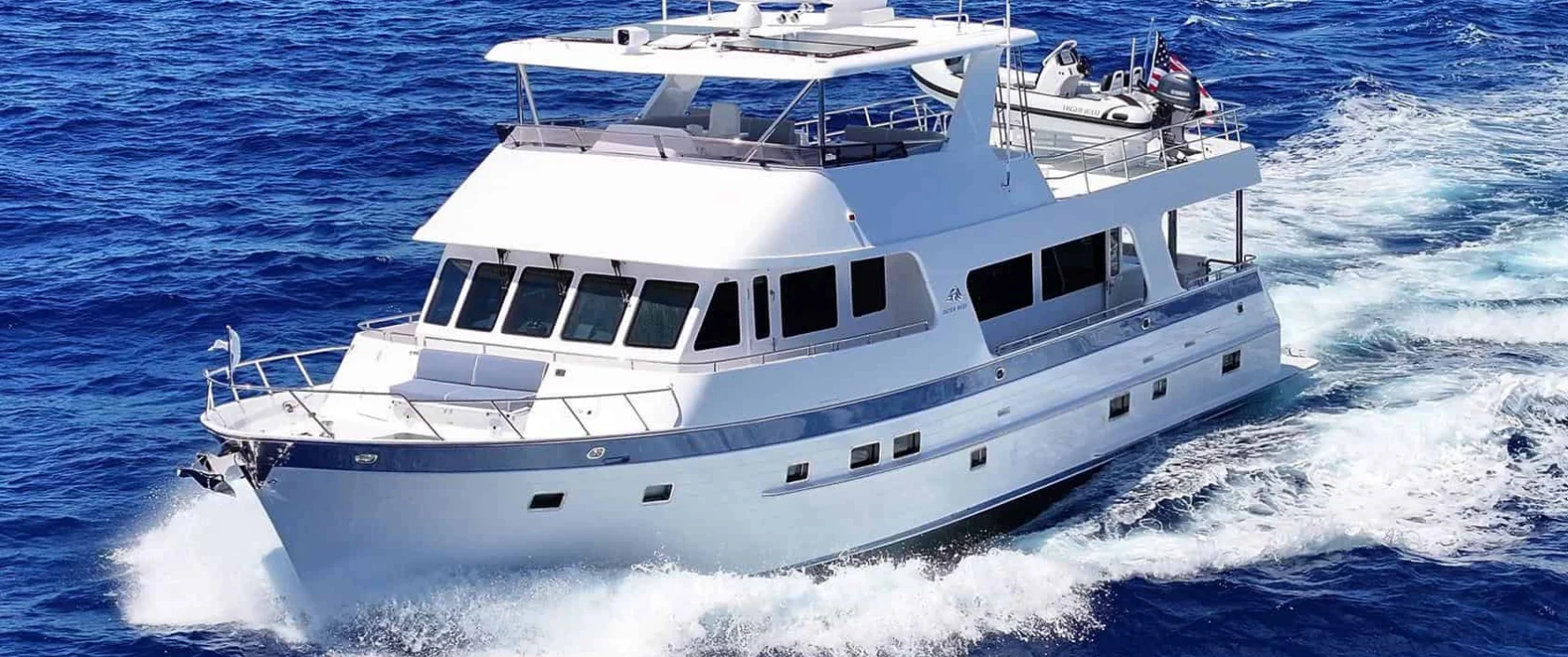Profile view of the 2024 Outer Reef Yachts 720 Motoryacht KNOT STABLE cruising underway on the ocean, showcasing its white hull and tri-deck design.
