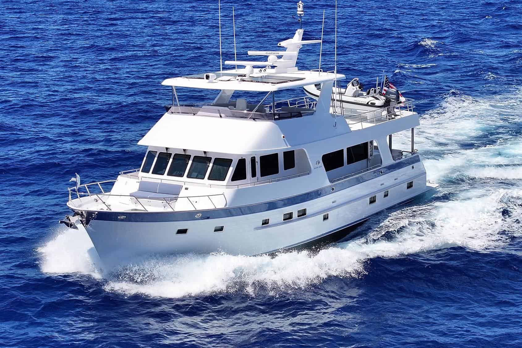 Profile view of the 2024 Outer Reef Yachts 720 Motoryacht KNOT STABLE cruising underway on the ocean, showcasing its white hull and tri-deck design.