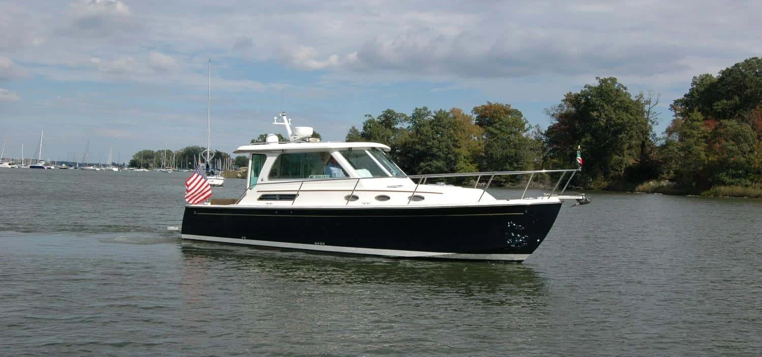 2014 Back Cove 34 Downeast cruiser yacht AU LAPIN AGILE featuring a dark blue hull cruising on calm water with an American flag on the stern