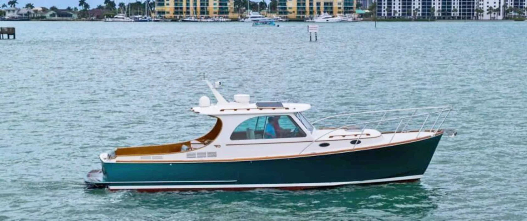 2014 Hinckley Picnic Boat 37 MKIII motor yacht RAMBLER II cruising on the water, showcasing its classic forest green hull, varnished teak toerail, and white pilothouse.