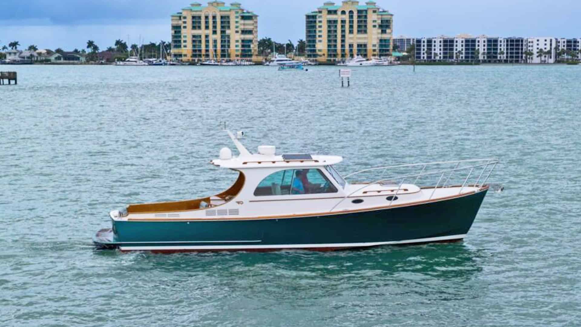 2014 Hinckley Picnic Boat 37 MKIII motor yacht RAMBLER II cruising on the water, showcasing its classic forest green hull, varnished teak toerail, and white pilothouse.
