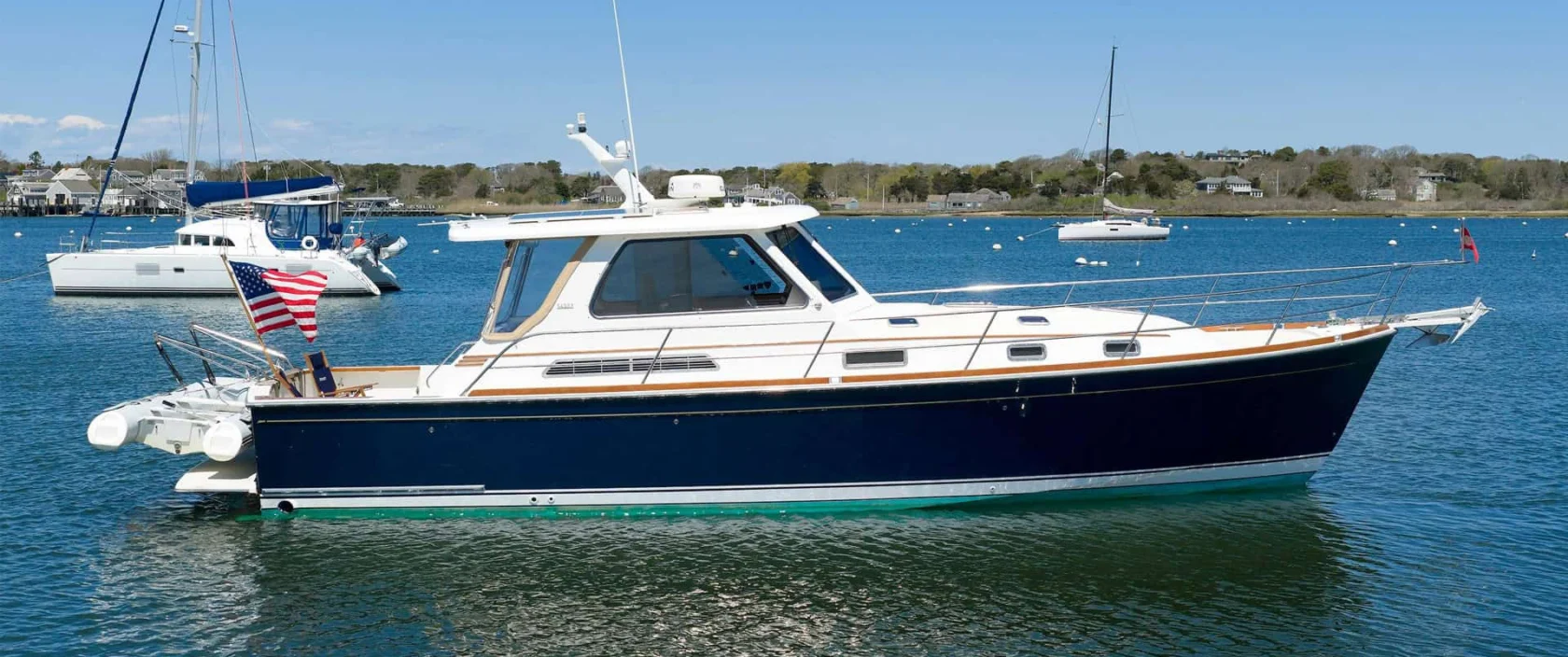 Flag Blue 2004 Sabre 42 Express Downeast yacht named MONOMΟΥ anchored on calm coastal water