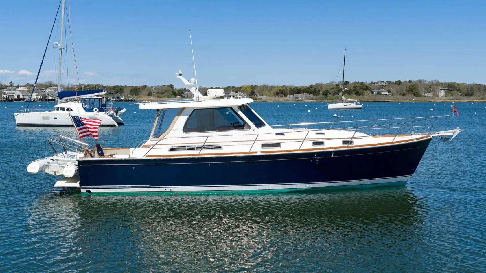 Flag Blue 2004 Sabre 42 Express Downeast yacht named MONOMΟΥ anchored on calm coastal water