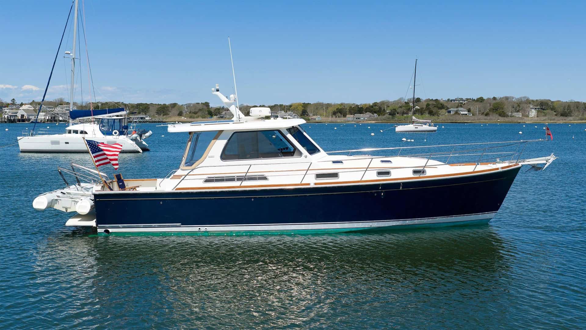 Flag Blue 2004 Sabre 42 Express Downeast yacht named MONOMΟΥ anchored on calm coastal water