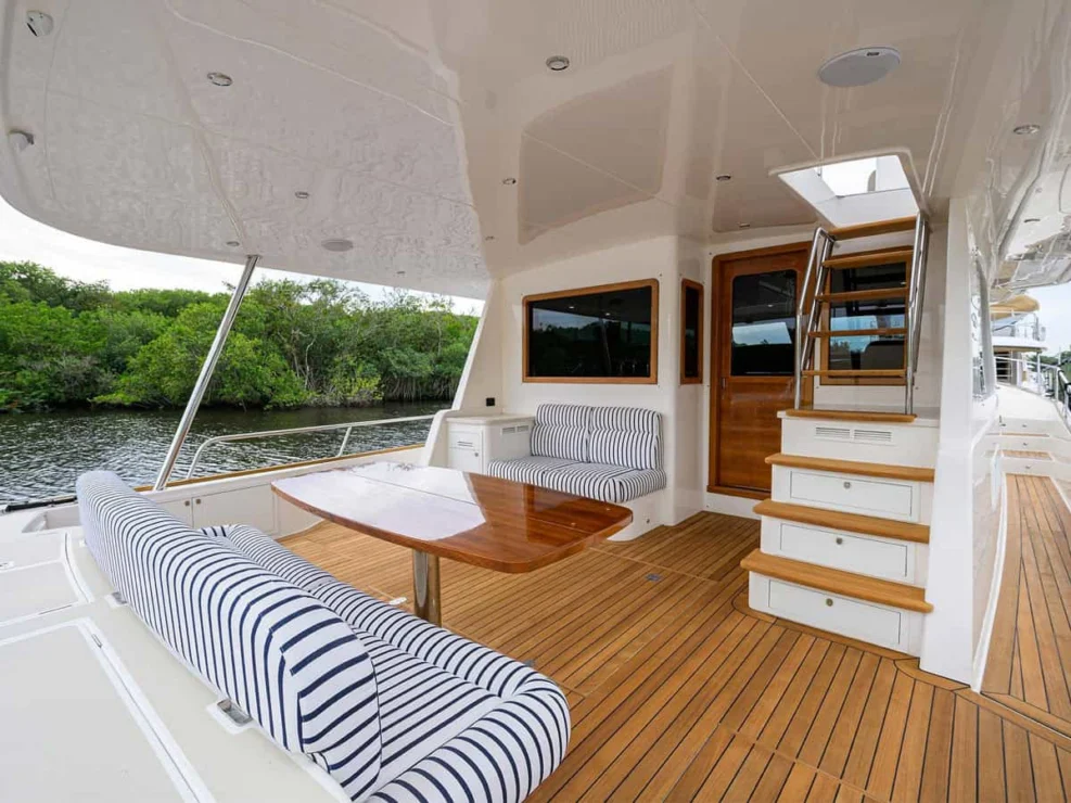 Aft deck cockpit of the Grand Banks 60 featuring striped bench seating and a glossy teak table