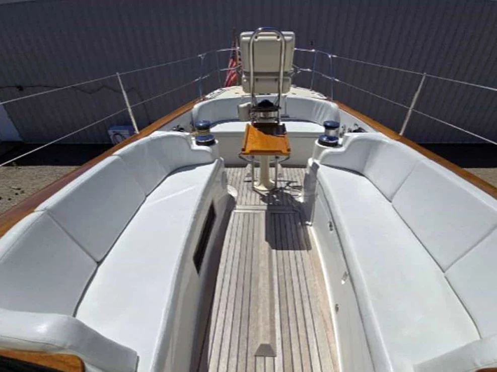 Symmetrical view of the Alerion 41 teak cockpit sole and white marine vinyl bench seating.