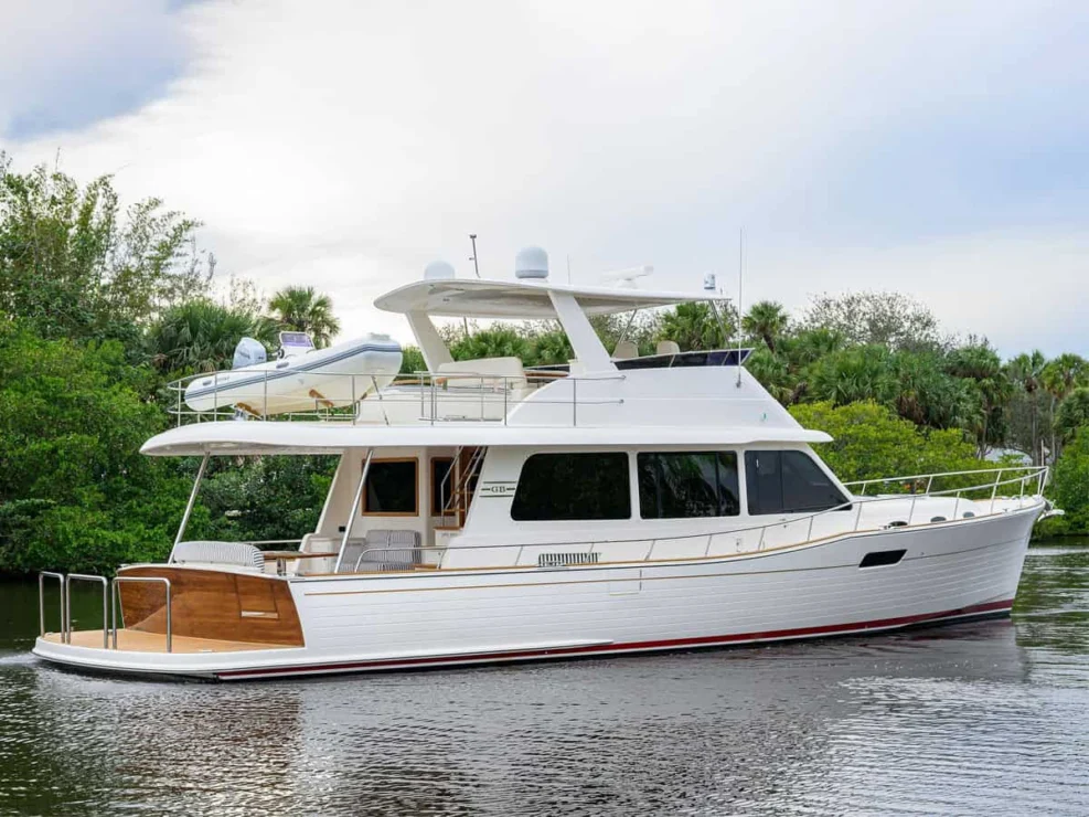 Three-quarter stern view of the white Grand Banks GB60 cruiser on the water, showing the flybridge