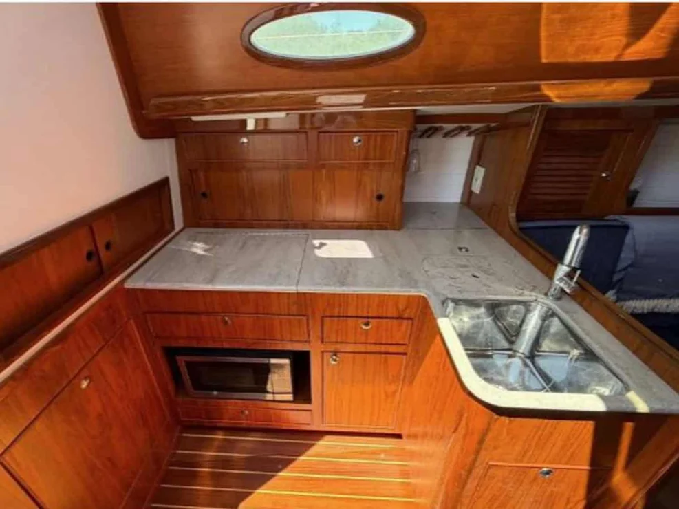 L-shaped galley of the Alerion 41 racer/cruiser, showcasing a stainless steel sink, solid surface countertops, and an built-in microwave.