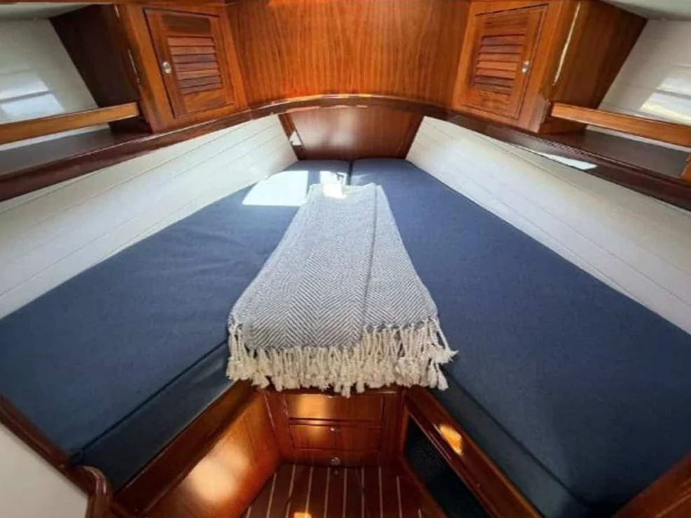 Spacious V-berth in the forward cabin of the Alerion 41 electric sailboat, complete with a custom woven blanket and under-bed storage.