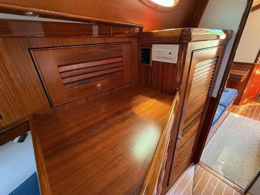 Compact navigation desk and electrical control center area featuring varnished cherry wood joinery inside the Alerion 41.