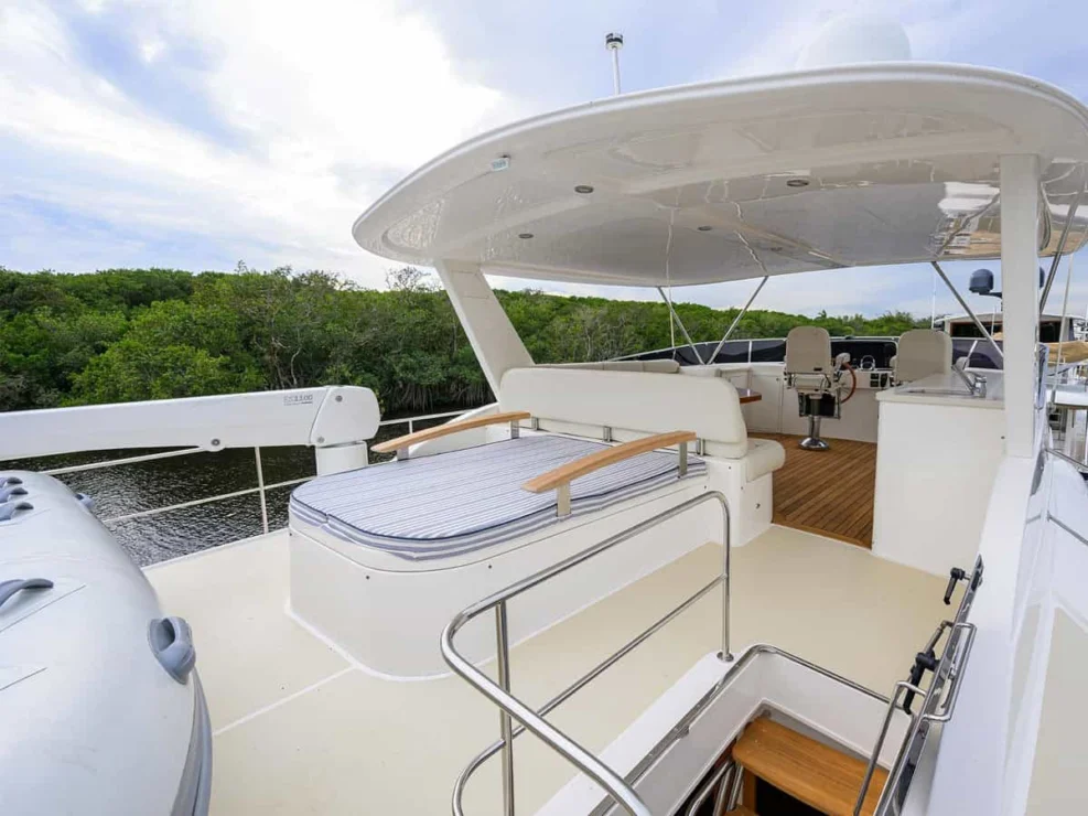 Open flybridge deck of the Grand Banks 60 yacht featuring a striped sun pad lounge and rigid tender